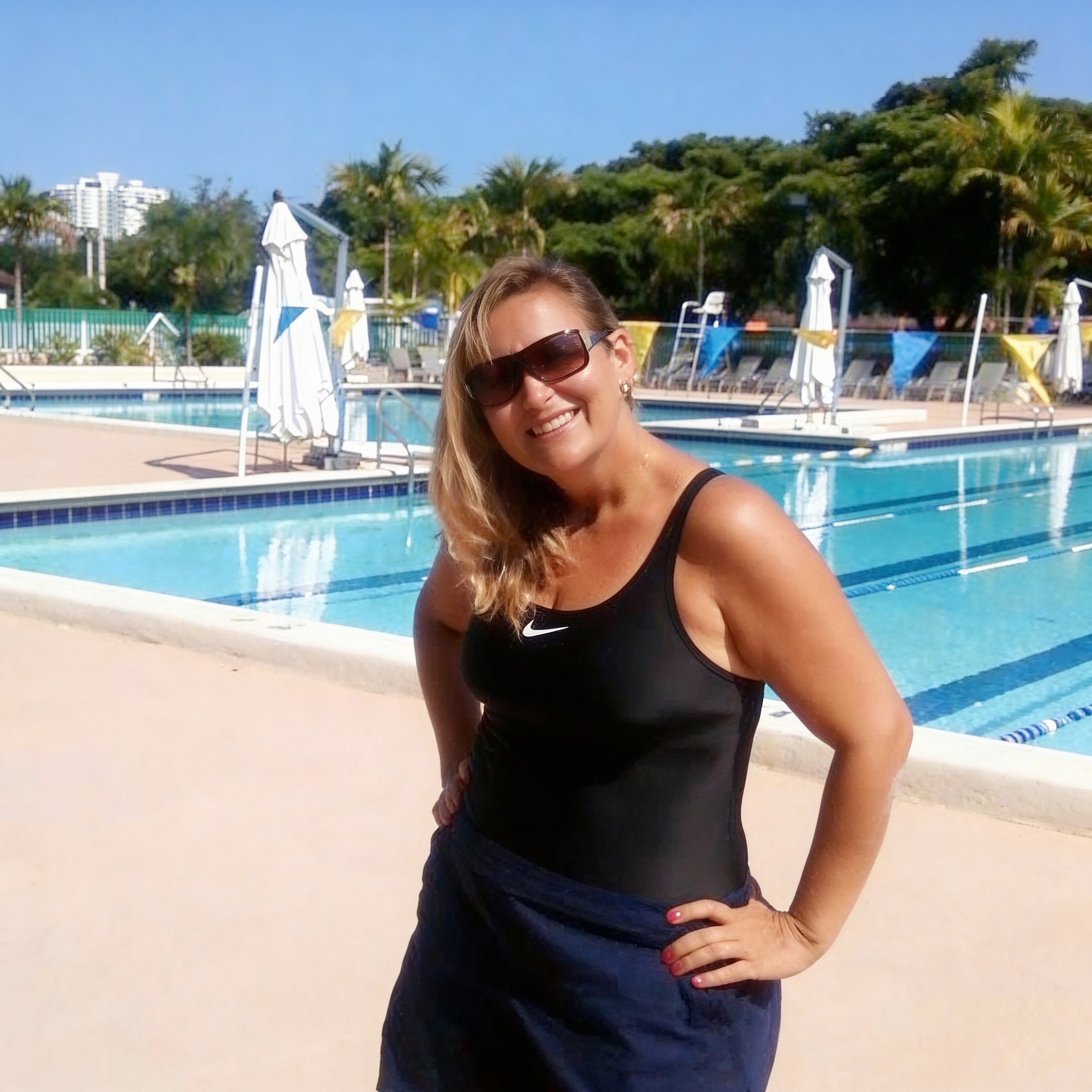 Friendly professional swim instructor smiling warmly at poolside